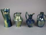 four different colored vases sitting next to each other on a table