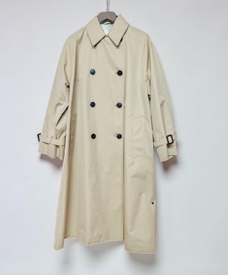 a beige trench coat hanging on a white wall