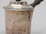 an old silver pot with a wooden handle on a white surface