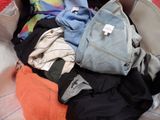 une valise remplie de vêtements et un sac à dos posé sur un lit