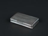 an image of a silver cigarette case sitting on a black surface