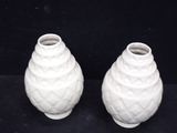 two white vases sitting next to each other on a black surface