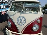 un minibus Volkswagen rouge et blanc garé devant un immeuble