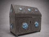une boîte en argent contenant des pierres bleues, posée sur une surface grise