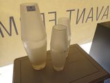 deux vases posés sur une table devant un panneau