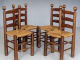 three wooden chairs with canes on them sit in a row