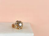 a close up of a gold and diamond ring on a white marble block