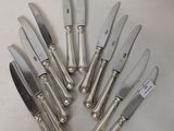 six silver plated knives are arranged in a circle on a white surface
