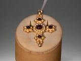 gold and amethorate cross with amethorate stones on top of a wooden box