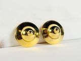 gold plated round stud earrings on a white marble surface