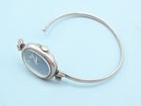 silver bracelet with a watch on it on a blue surface