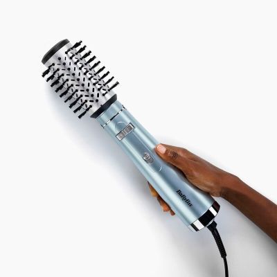 a person holding a hair dryer in their hand on a white surface