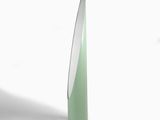 un vase vert avec un couvercle blanc posé sur une surface blanche