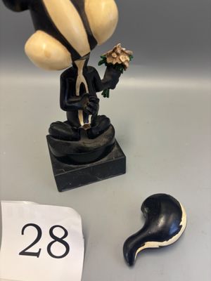 a figurine of a man in a tuxedo with a flower in his hand