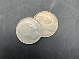 two coins sitting on a table next to each other