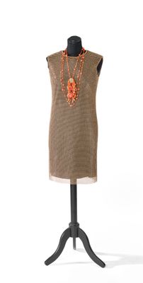 robe marron posée sur un mannequin, ornée de perles orange et d'un collier