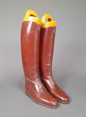 pair of brown leather boots with yellow soles on a gray surface