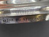someone is holding a silver plate with the words made de melons engraved on it