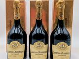 trois bouteilles de champagne devant un coffret doré