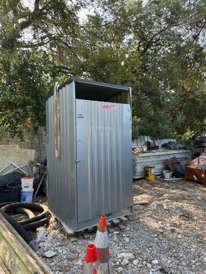 une cabane de toilettes en métal installée au milieu d'une cour