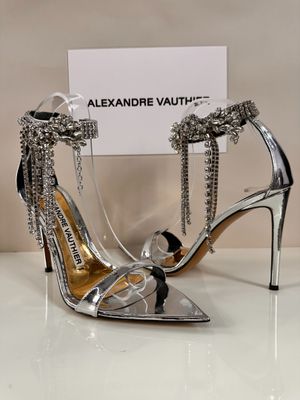 silver high heeled shoes with chains on them and a business card in front of them