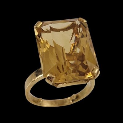 une image représentant une bague sertie d'une pierre jaune sur fond noir