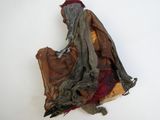 une sculpture représentant un vieil homme assis sur un morceau de tissu
