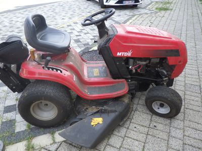 une tondeuse à gazon rouge garée sur le bord de la route