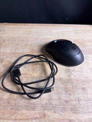 a black mouse and a black cord on a wooden table