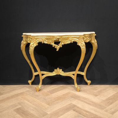 a gold console table with a marble top on a wooden floor