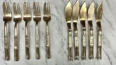 six forks and six knives are lined up on a marble surface