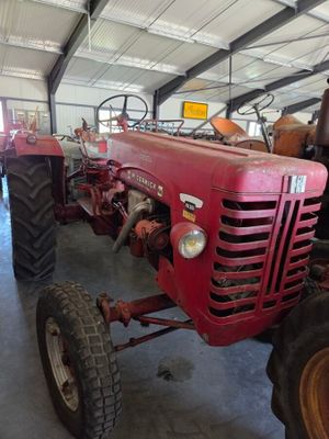un tracteur rouge garé à l'intérieur d'un bâtiment, dans un garage