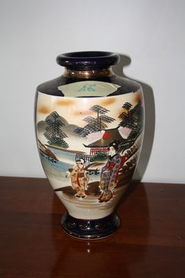 a vase with a painting on it sitting on a table