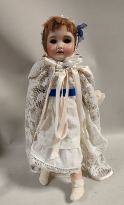 une image représentant une poupée vêtue d'une robe blanche et d'un nœud bleu