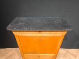 a small wooden cabinet with a marble top on a hard wood floor