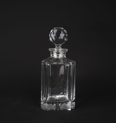 une bouteille en verre transparent avec un bouchon en cristal sur fond noir