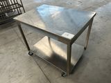 une table en acier inoxydable montée sur roulettes dans un entrepôt