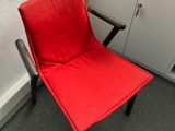 une chaise rouge qui se trouve dans le coin d'une pièce