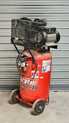 un compresseur d'air posé sur un chariot devant la porte d'un garage