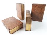 three old books sitting next to each other on a white surface