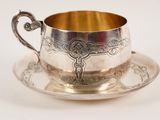 a silver cup and saucer sitting on a saucer