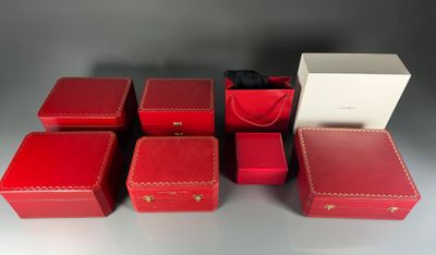 six boîtes rouges munies de poignées sont disposées sur une table