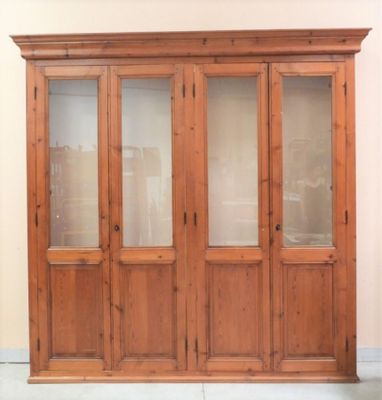 un grand meuble en bois avec des portes en verre dans une pièce