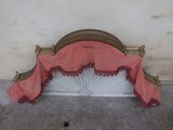 a pink and gold bed with a fan on the headboard