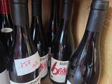 several bottles of red wine are lined up on a wooden shelf