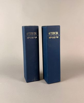 deux boîtes bleues de parfum posées l'une à côté de l'autre sur une surface blanche