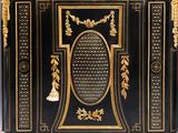a black and gold decorated cabinet with a bell on top