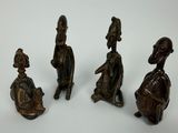 quatre figurines en bronze représentant des personnes assises sur une surface blanche