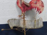 a metal rooster on top of a sign on the side of a building