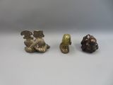 three small figurines of animals sitting next to each other on a white surface